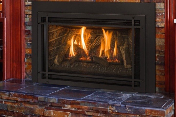 Fireplace insert burning in a rustic stacked-stone hearth