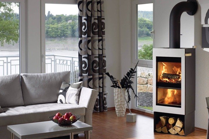 Modern wood stove burning in a bright living room with large windows