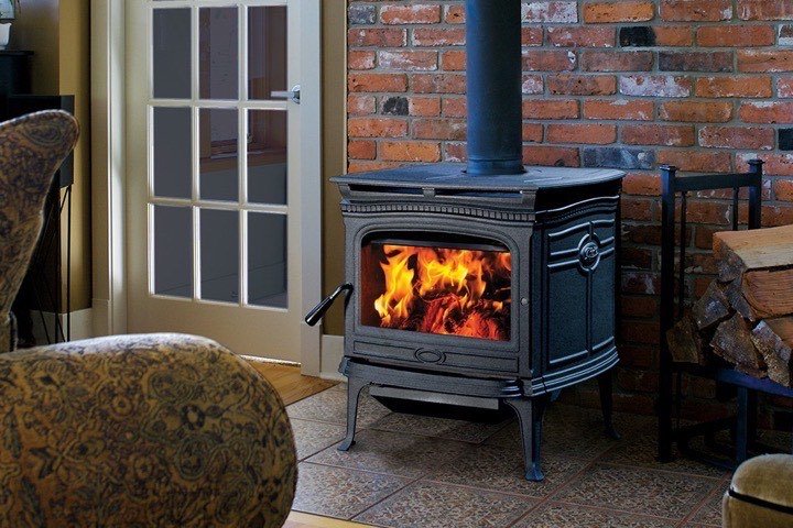 Pacific Energy Alderlea cast iron wood stove burning in a brick-walled living room