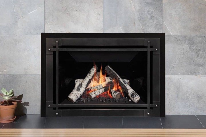 Valor gas fireplace insert with birch logs set in a grey stone surround