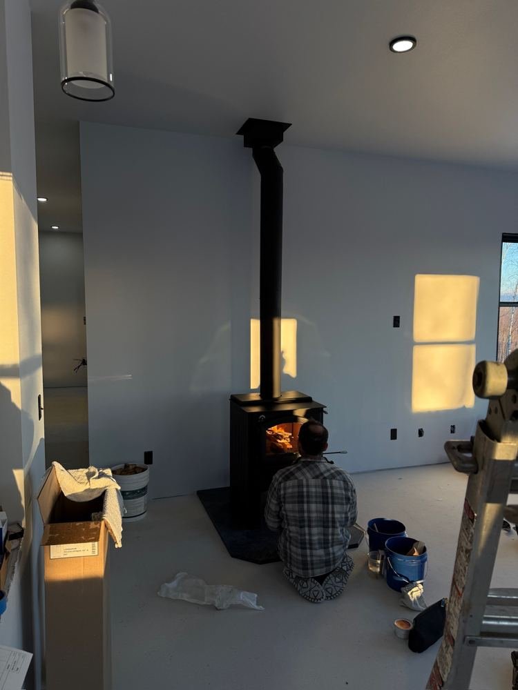 Technician completing a wood stove installation in a new build at sunset